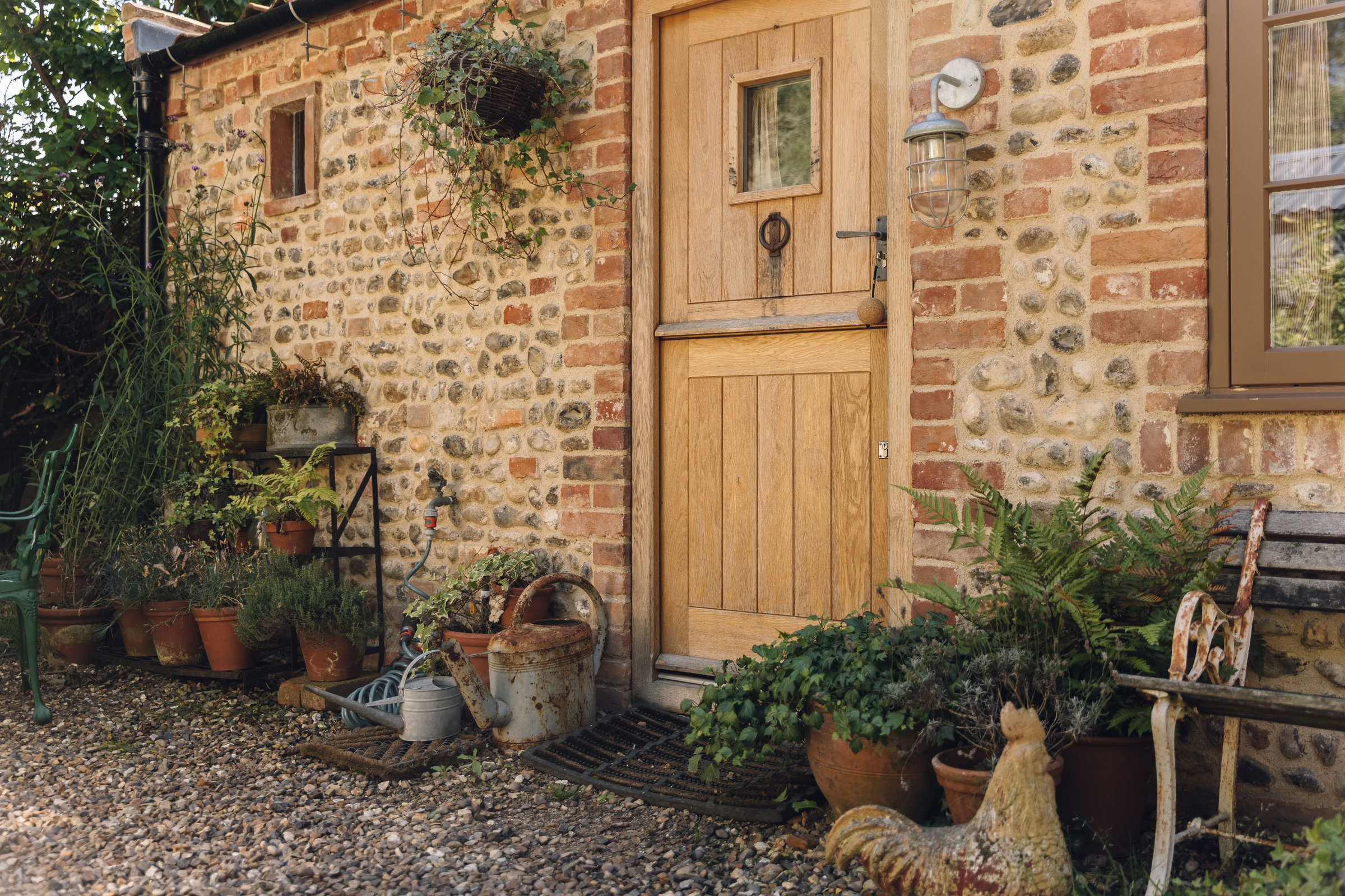 The oak front door with pots of plants