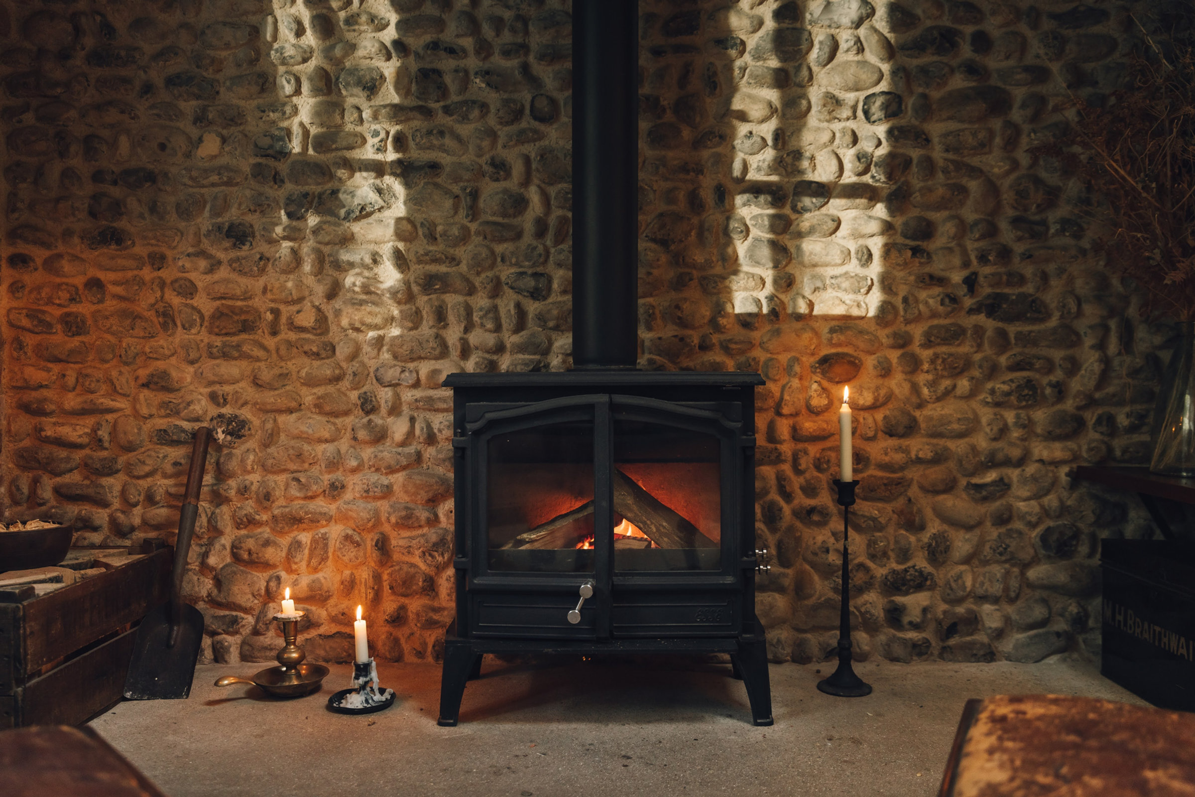The woodburner glowing against the ancient flint wall
