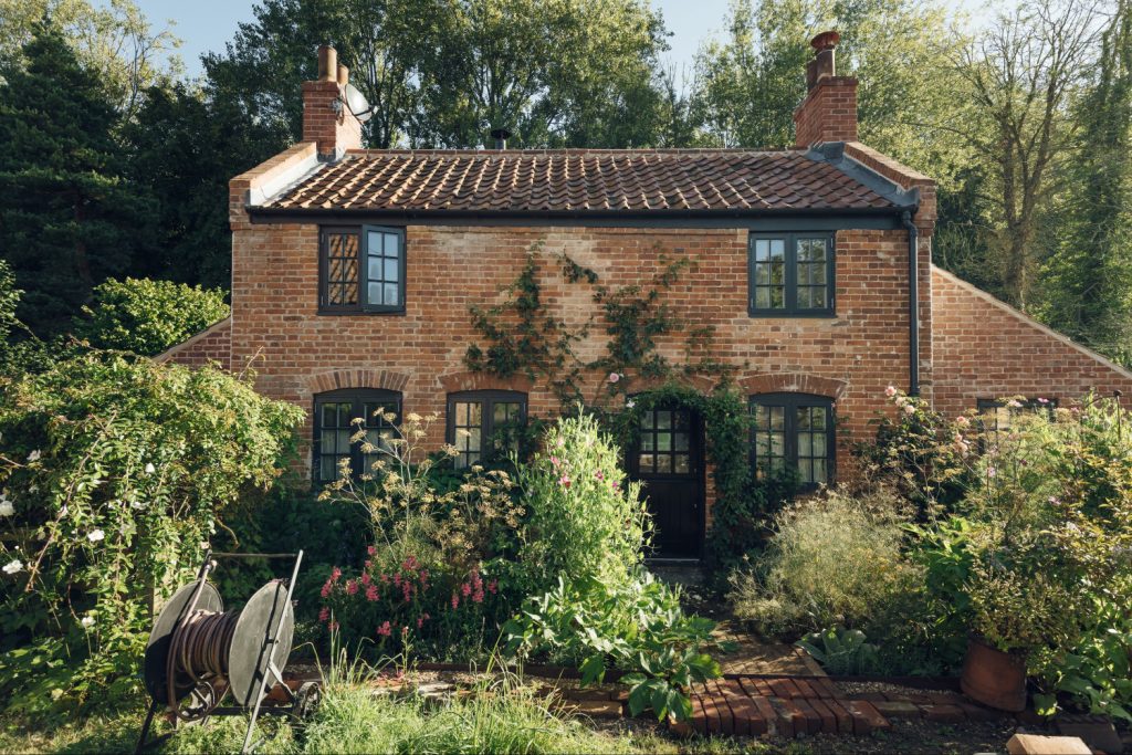 Riverbank's red-brick front, wrapped in roses and cottage-garden plants