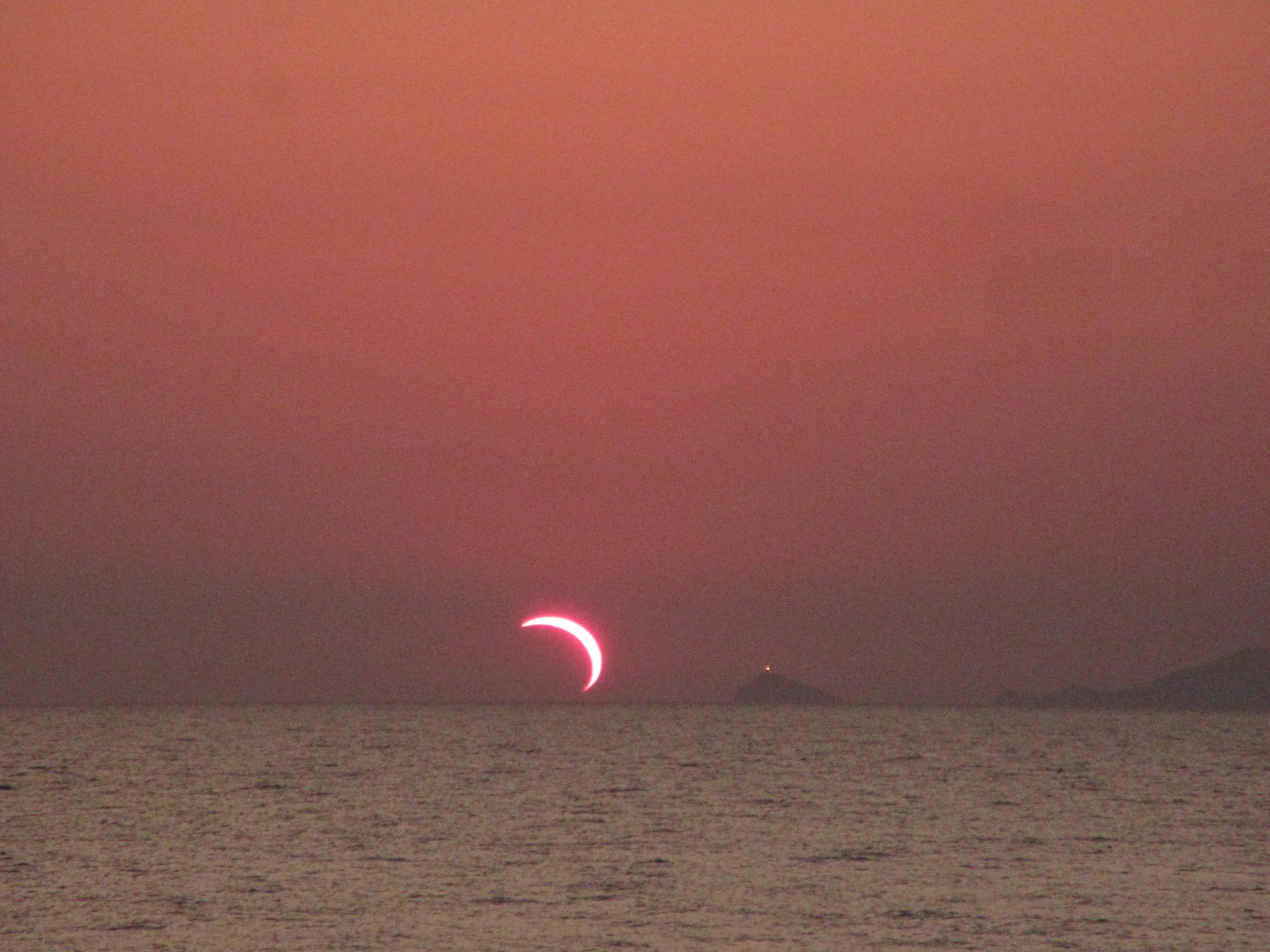 The sun reduced to a thin crescent during the partial eclipse of 12 August 2026, low in a hazy evening sky