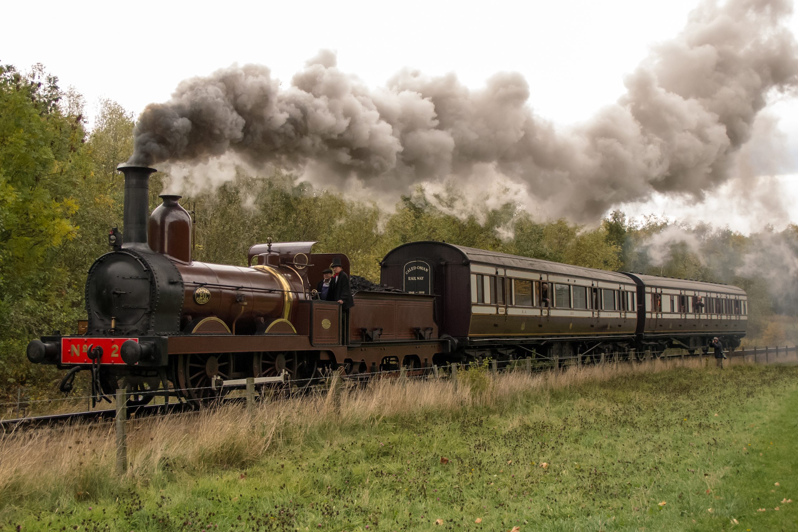 Furness Railway No 20, a red steam locomotive, pulling vintage carriages